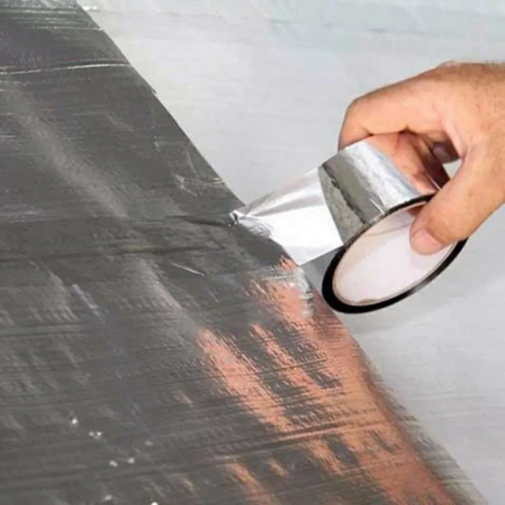 Detalhe da superfície aluminizada e adesivo acrílico de alta aderência da fita para refrigeração e mantas.